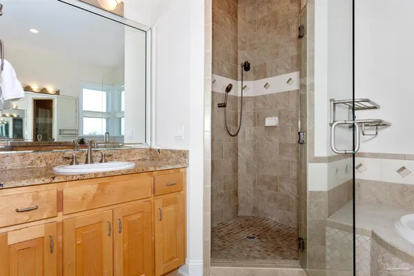 a bathroom with a granite countertop sink a mirror and shower