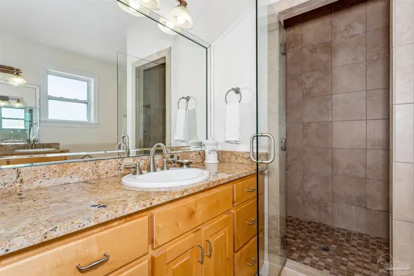 a bathroom with a granite countertop sink a mirror and shower