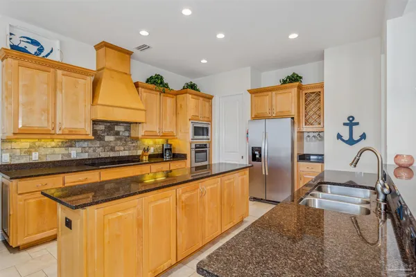 a kitchen with stainless steel appliances granite countertop a sink and a refrigerator