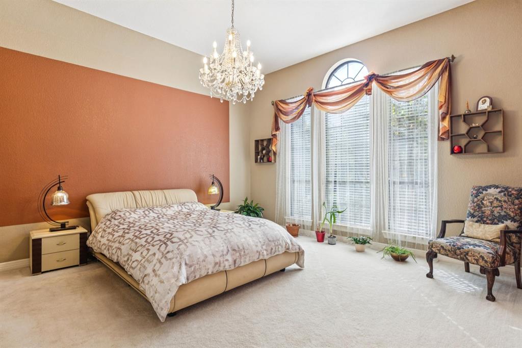 3825 Montecito Drive Denton, TX 76205 - Photo 19 of 37 a bedroom with a bed and a chandelier