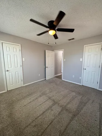 an empty room with ceiling fan and window