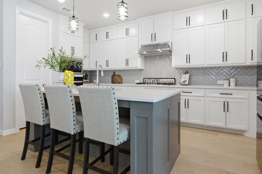910 Winter Cherry Lane Haslet, TX 76052 - Photo 14 of 40 a kitchen with stainless steel appliances kitchen island granite countertop a table chairs in it white cabinets and a granite counter tops