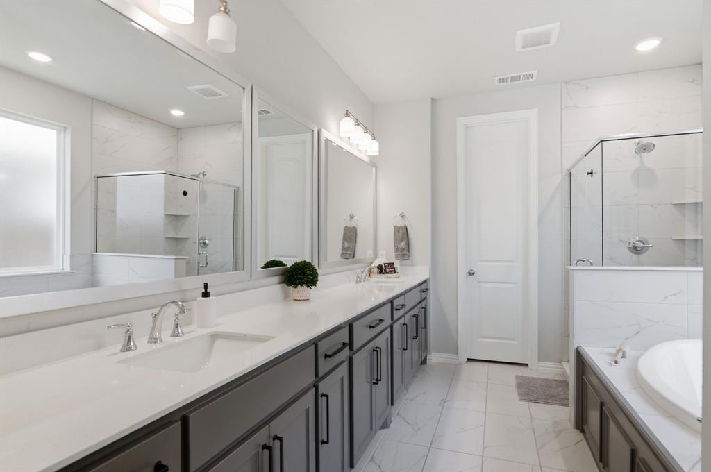910 Winter Cherry Lane Haslet, TX 76052 - Photo 21 of 40 a bathroom with a double vanity sink a large mirror and a shower