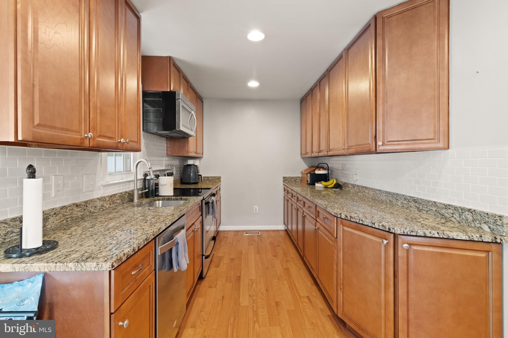 8573 Tyrolean Way Springfield, VA 22153 - Photo 9 of 32 a kitchen with stainless steel appliances granite countertop a sink a stove and a wooden cabinets