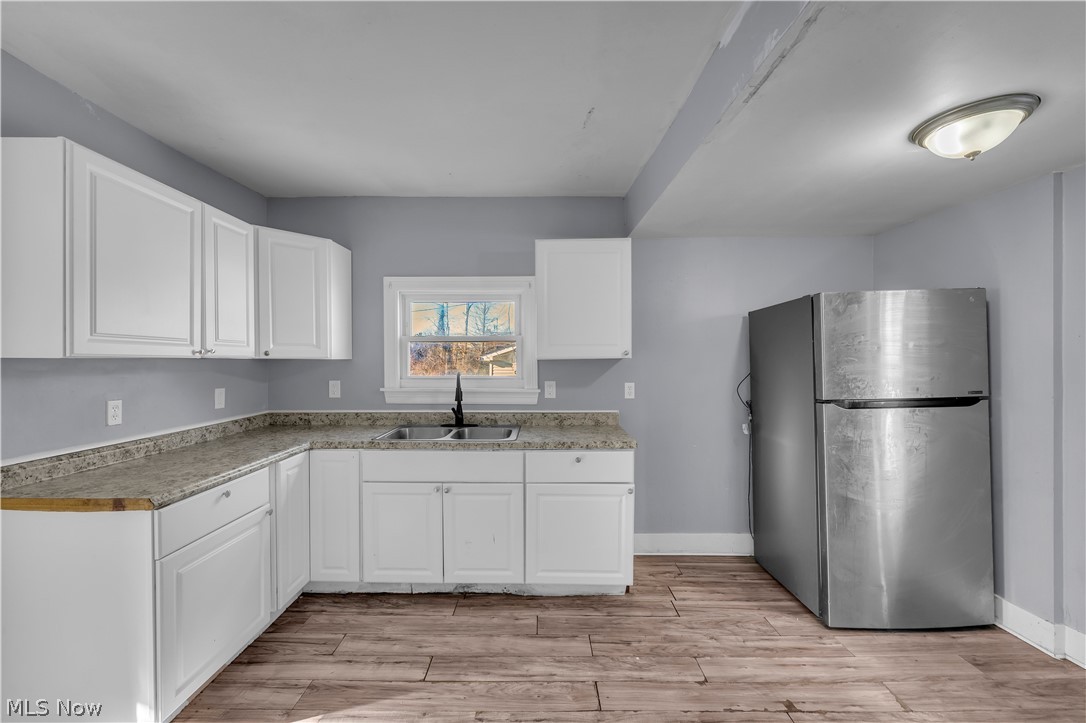 1858 Rudwick Road Cleveland, OH 44112 - Photo 12 of 36 Kitchen featuring freestanding refrigerator, white cabinetry, light wood finished floors, and light countertops