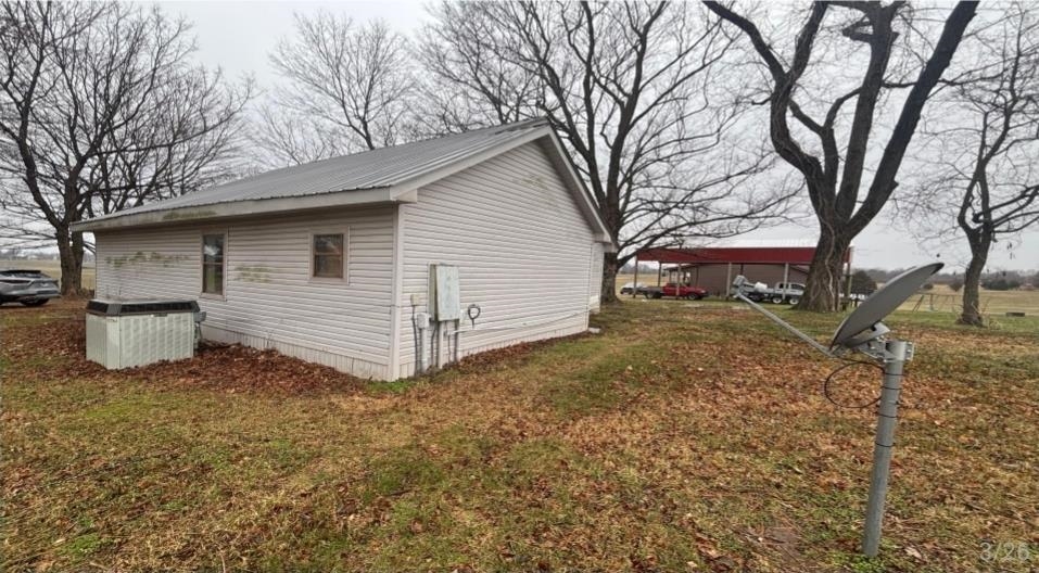836 Mill Creek Road Troy, TN 38260 - Photo 1 of 6 White siding exterior with a metal roof, featuring multiple windows and an external utility panel