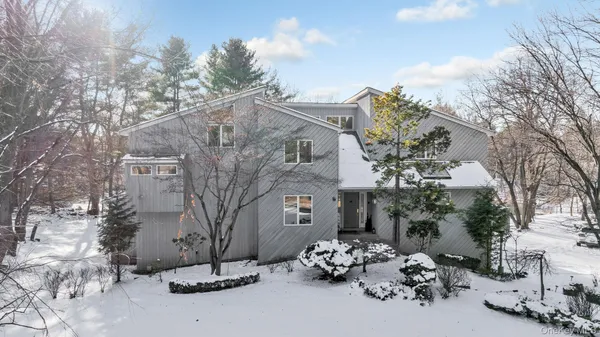 a view of a white house with a large tree and many windows