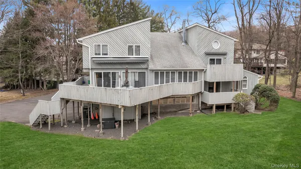 a view of a house with a yard deck and large trees