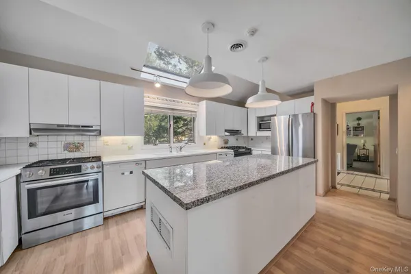 a kitchen with stainless steel appliances granite countertop a sink a stove and a wooden floors