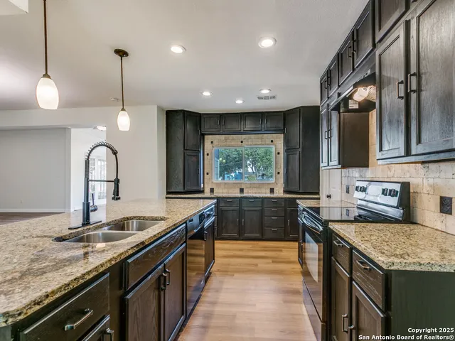a kitchen with stainless steel appliances granite countertop a sink a stove and a wooden floors