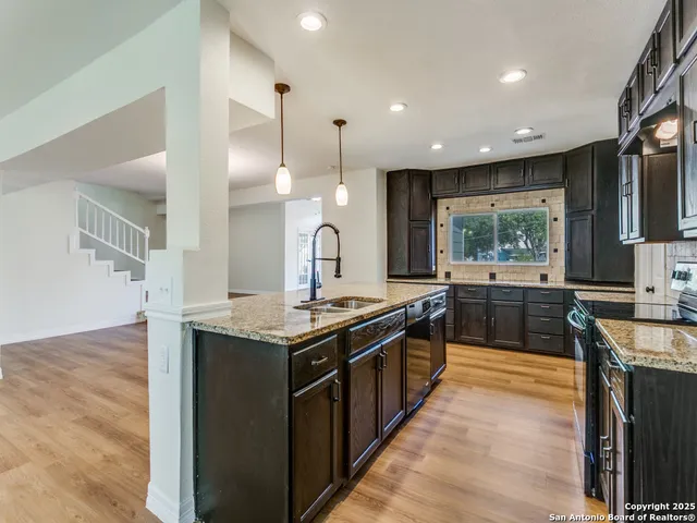 a kitchen with stainless steel appliances granite countertop wooden cabinets a sink a stove a counter top and a floors
