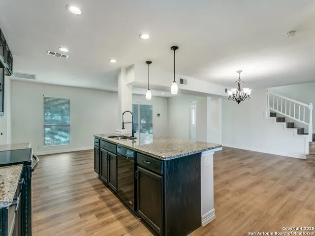 a kitchen with stainless steel appliances granite countertop a sink a stove a refrigerator and a window
