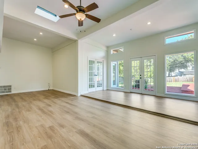 an empty room with wooden floor and windows