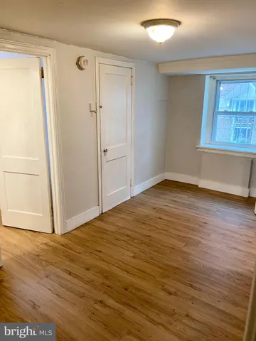 an empty room with wooden floor cabinet and windows