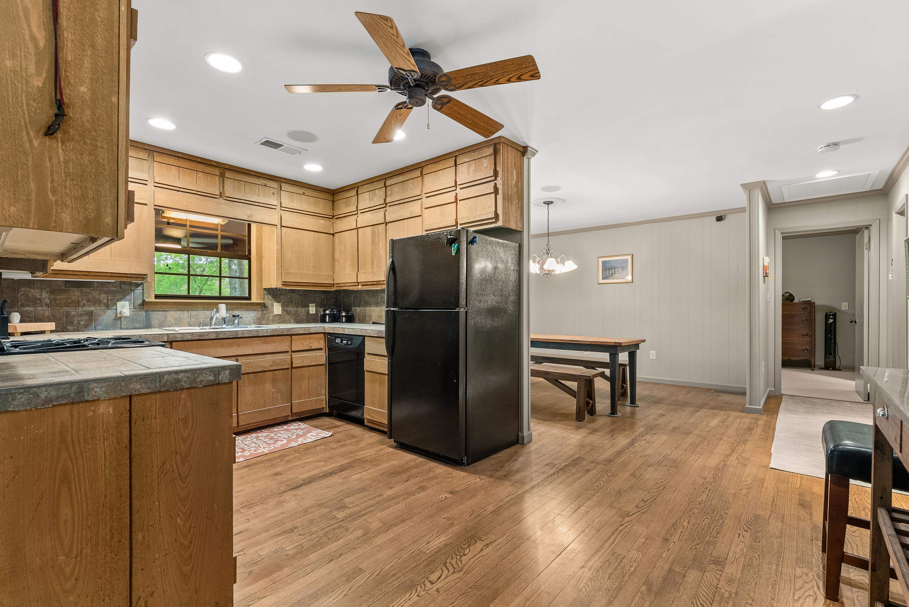 2275 Cypress Road Pocahontas, TN 38061 - Photo 20 of 34 Kitchen with black appliances, light wood-type flooring, decorative backsplash, tile countertops, and a ceiling fan