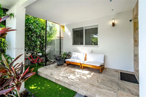a living room with patio furniture and a floor to ceiling window