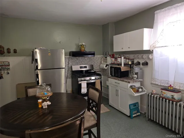 a kitchen with stainless steel appliances granite countertop a sink dishwasher stove a refrigerator a dining table and chairs with wooden floor