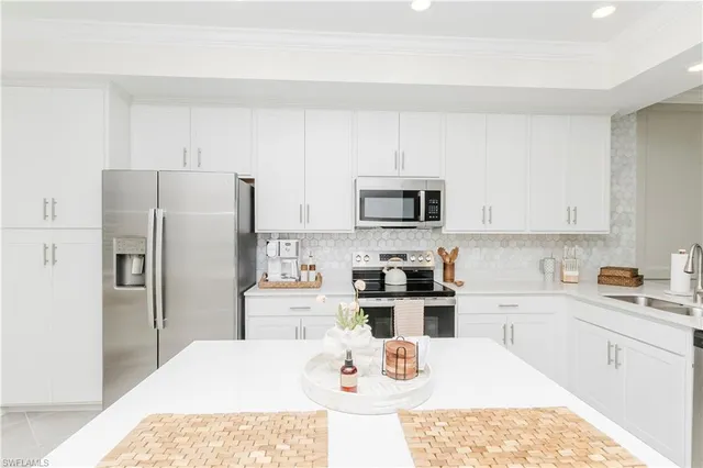 a kitchen with white cabinets and stainless steel appliances