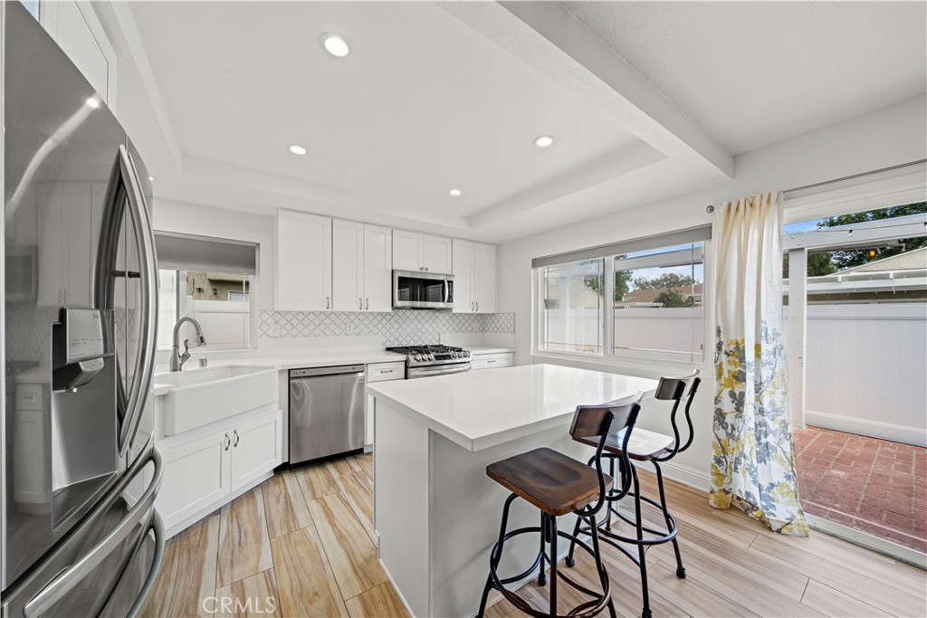 24243 Lema Drive Valencia, CA 91355 - Photo 2 of 37 a kitchen with stainless steel appliances a stove a sink dishwasher a refrigerator with white cabinets and wooden floor