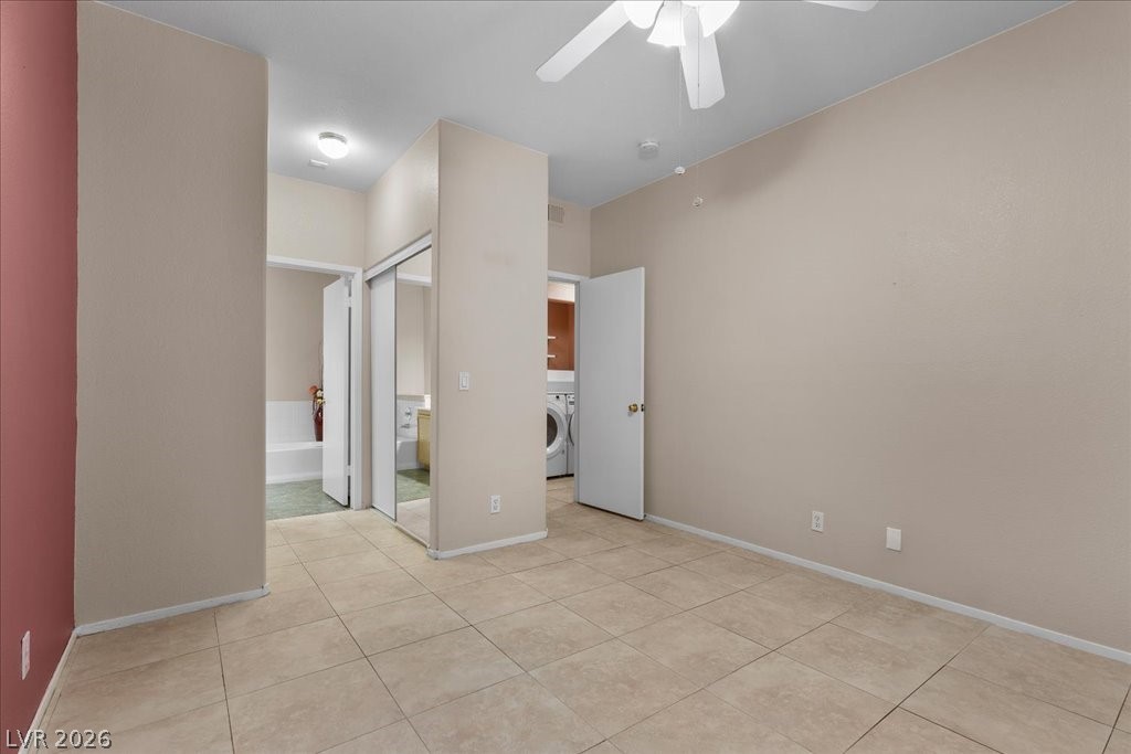 2201 Ramsgate Drive, Unit 818 Henderson, NV 89074 - Photo 12 of 31 Unfurnished bedroom with a closet, a ceiling fan, ensuite bathroom, light tile patterned floors, and washer / dryer