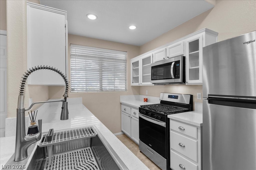 2201 Ramsgate Drive, Unit 818 Henderson, NV 89074 - Photo 5 of 31 Kitchen with stainless steel appliances, white cabinetry, glass insert cabinets, light stone counters, and recessed lighting