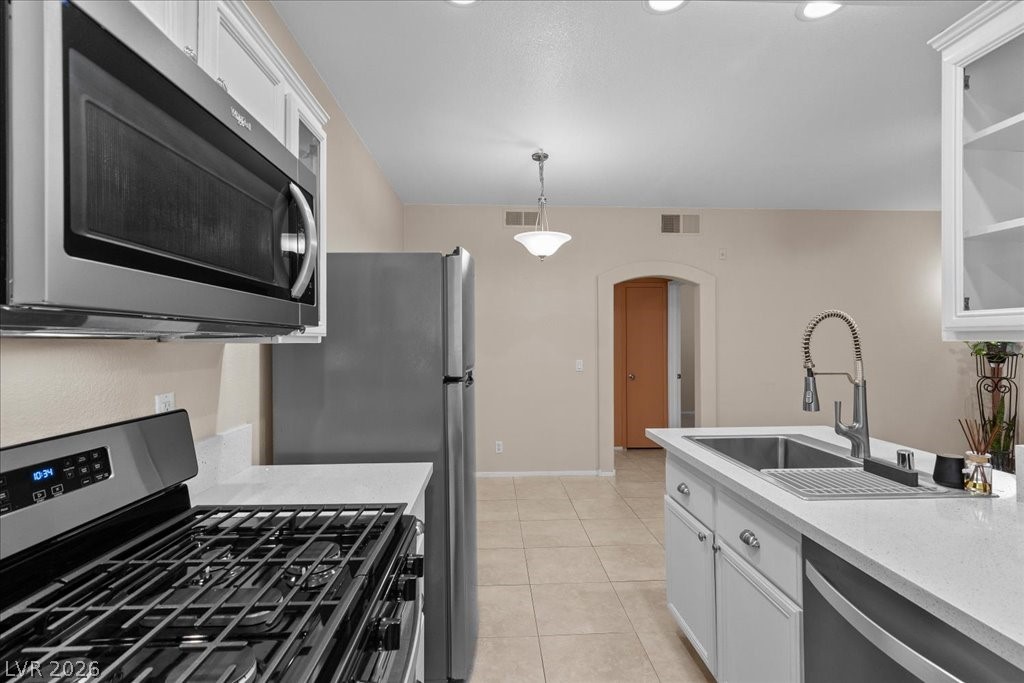 2201 Ramsgate Drive, Unit 818 Henderson, NV 89074 - Photo 9 of 31 Kitchen with stainless steel appliances, white cabinetry, arched walkways, and light stone countertops