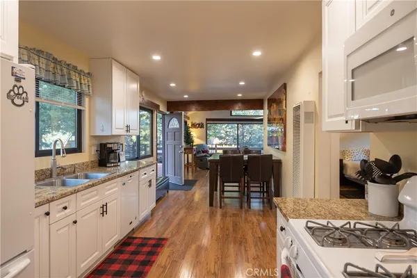 a kitchen with stainless steel appliances granite countertop sink stove refrigerator and wooden floor