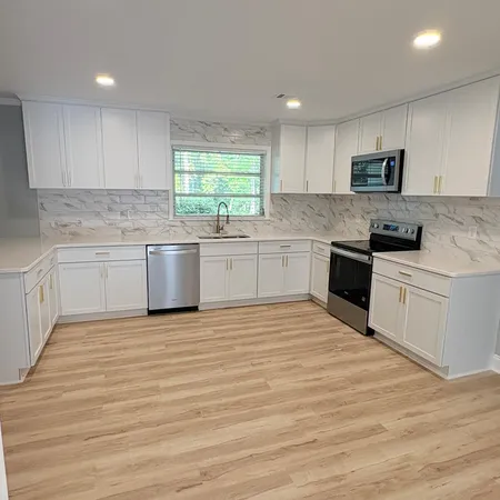 a large kitchen with stainless steel appliances granite countertop a stove top oven a sink dishwasher and a refrigerator