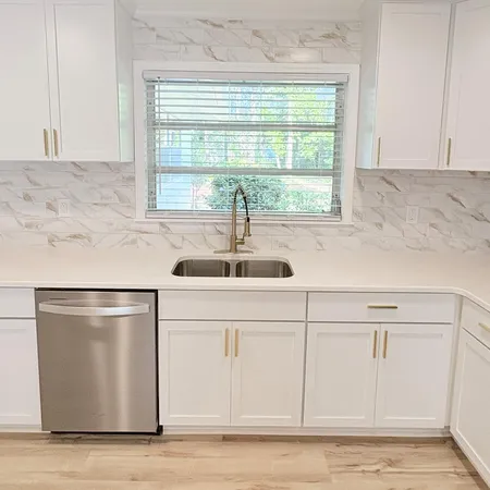 a kitchen with stainless steel appliances white cabinets and a window