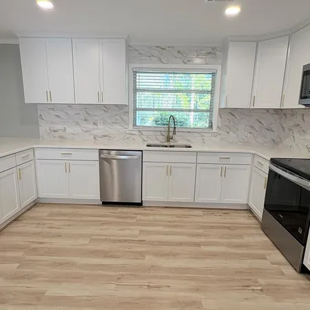 a kitchen with granite countertop white cabinets sink and window