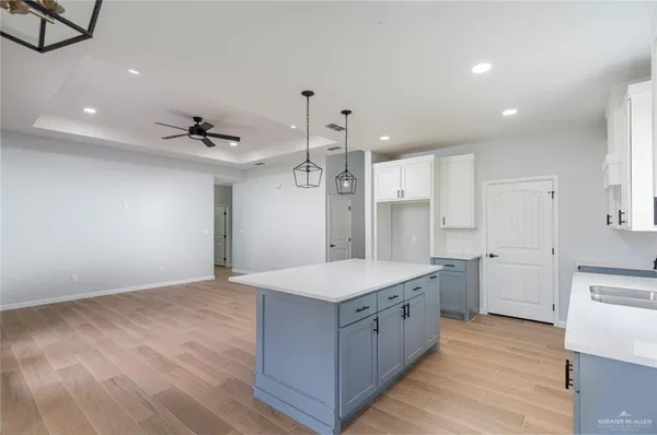 a large kitchen with a large counter top a sink stainless steel appliances and cabinets
