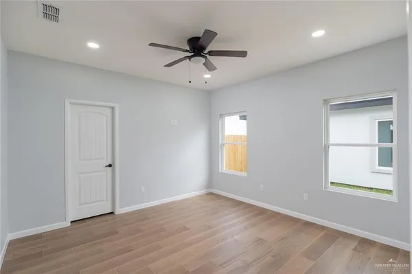 a view of an empty room with a window and wooden floor