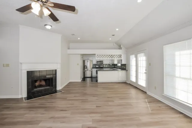 a view of an empty room with kitchen and fireplace
