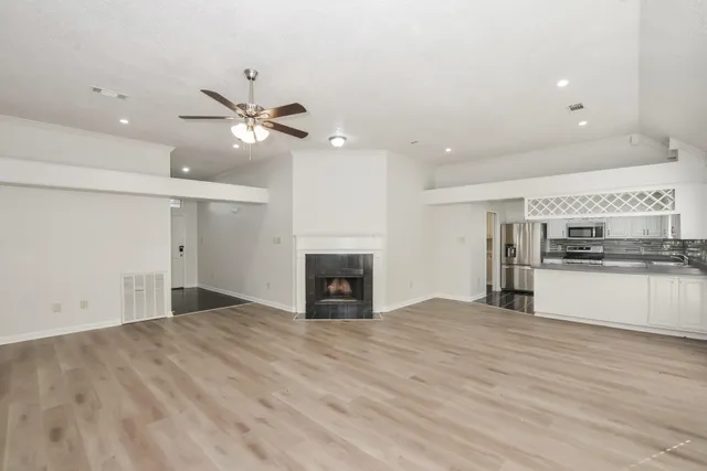 a view of kitchen and empty room with fireplace