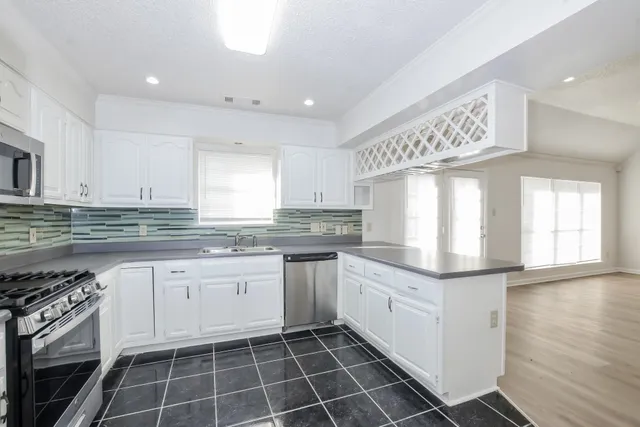 a kitchen with granite countertop stainless steel appliances a sink and cabinets