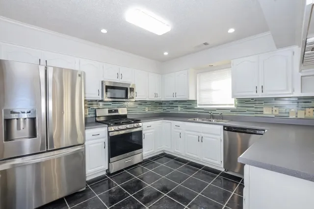 a kitchen with granite countertop stainless steel appliances a stove a sink and a refrigerator