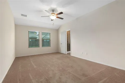 an empty room with windows and chandelier fan