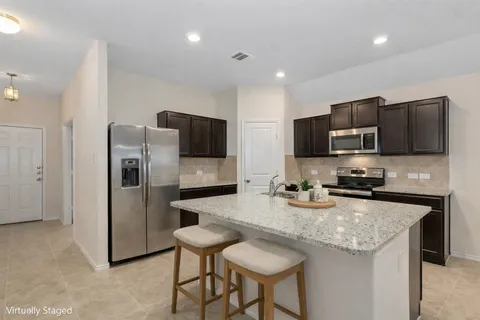 a kitchen with stainless steel appliances granite countertop a refrigerator a stove a sink a microwave and a refrigerator