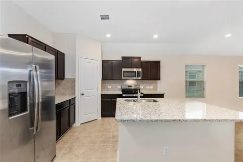 a large kitchen with granite countertop a refrigerator and a stove top oven