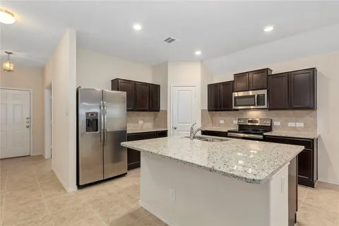 a kitchen with stainless steel appliances granite countertop a refrigerator a stove a microwave a sink and dishwasher