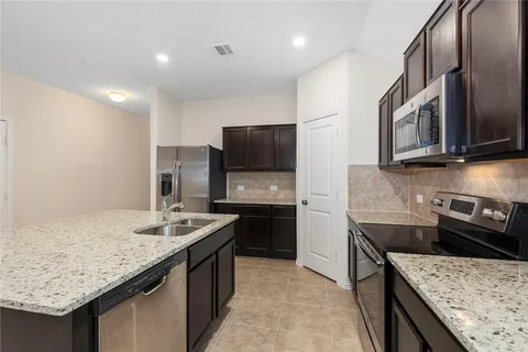 a kitchen with stainless steel appliances granite countertop a sink stove and refrigerator