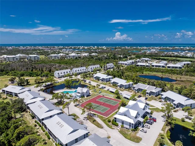 an aerial view of a city with lots of residential buildings ocean and mountain view in back