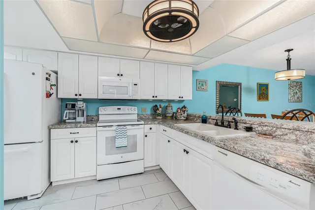 a kitchen with granite countertop white cabinets white stainless steel appliances and a sink