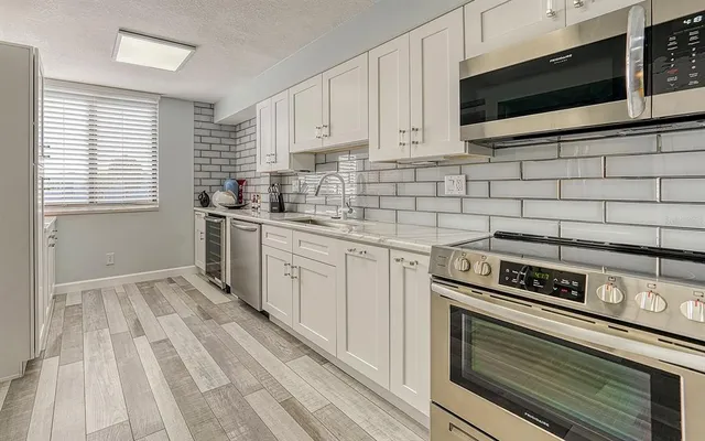 a kitchen with stainless steel appliances a stove a sink and white cabinets