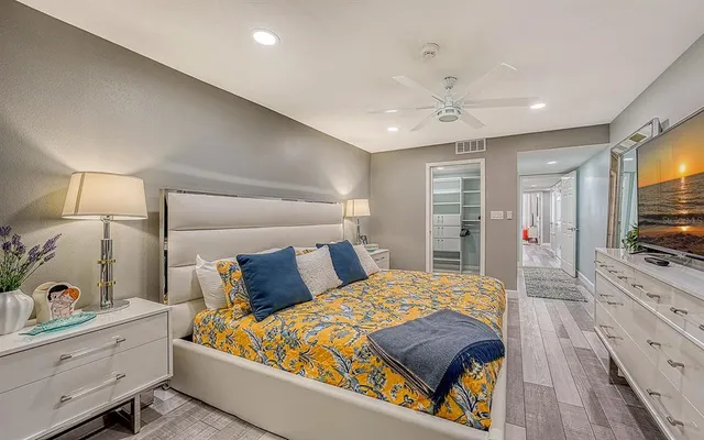 a bedroom with a large bed and a flat tv screen on dresser