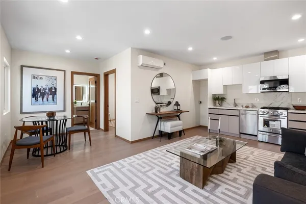 a living room with furniture and kitchen view with wooden floor