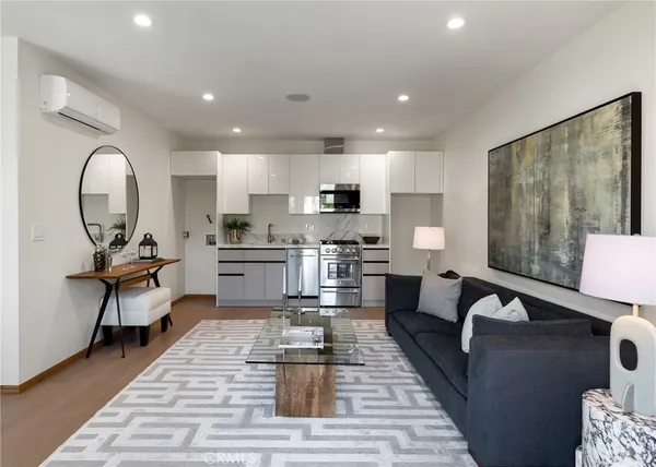 a living room with furniture a rug kitchen view and a large window
