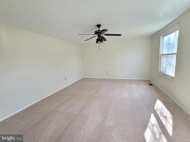an empty room with windows and fan