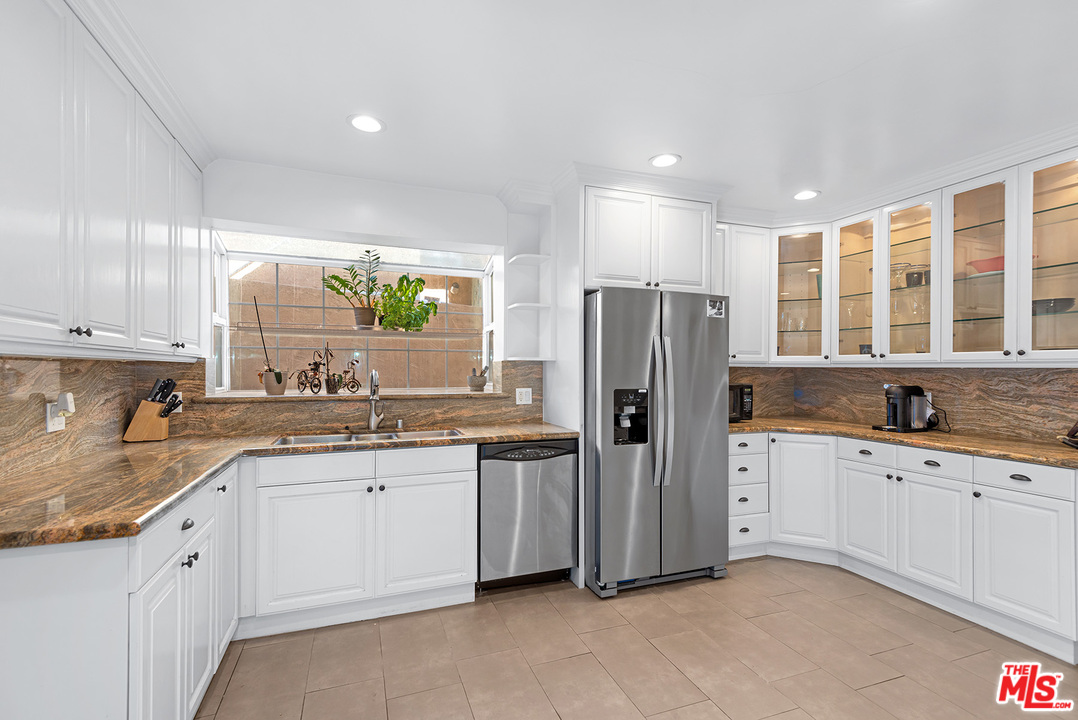 1307 South Rimpau Boulevard Los Angeles, CA 90019 - Photo 32 of 54 a kitchen with stainless steel appliances granite countertop a refrigerator and sink