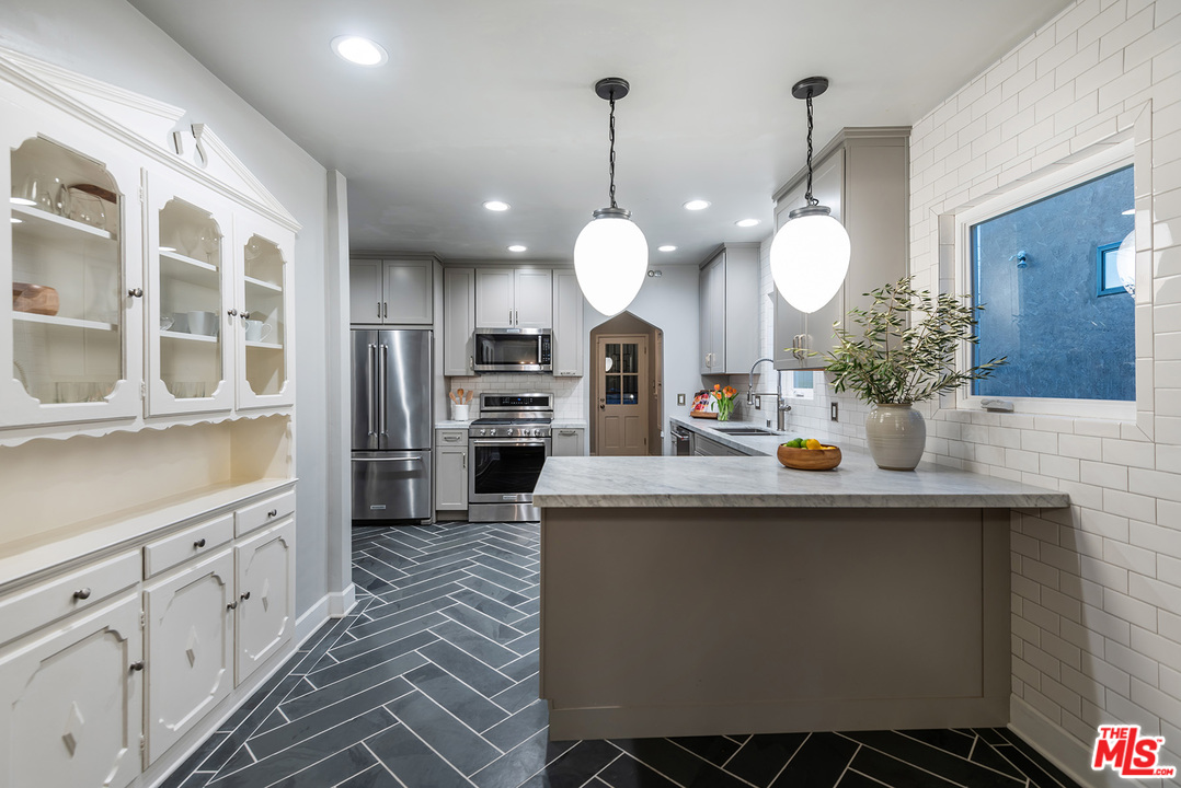 1307 South Rimpau Boulevard Los Angeles, CA 90019 - Photo 49 of 54 a kitchen with stainless steel appliances granite countertop a sink a stove and a wooden floors